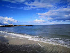 A beach with waves, a pier, and a yacht. - 5 Person Holiday Home in Albaek (Aalbaek)