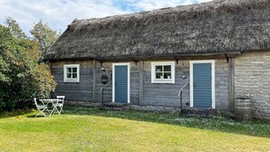 A rustic wooden cottage with a thatched roof, a small garden, and a picnic table. - 3 Person Holiday Home in Lottorp (Löttorp)