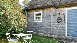 A rustic wooden cottage with a thatched roof, a small window, and a blue door. - 3 Person Holiday Home in Lottorp (Löttorp)