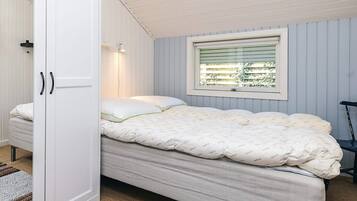 Un dormitorio con cama, ventana con persianas, una silla y un armario.