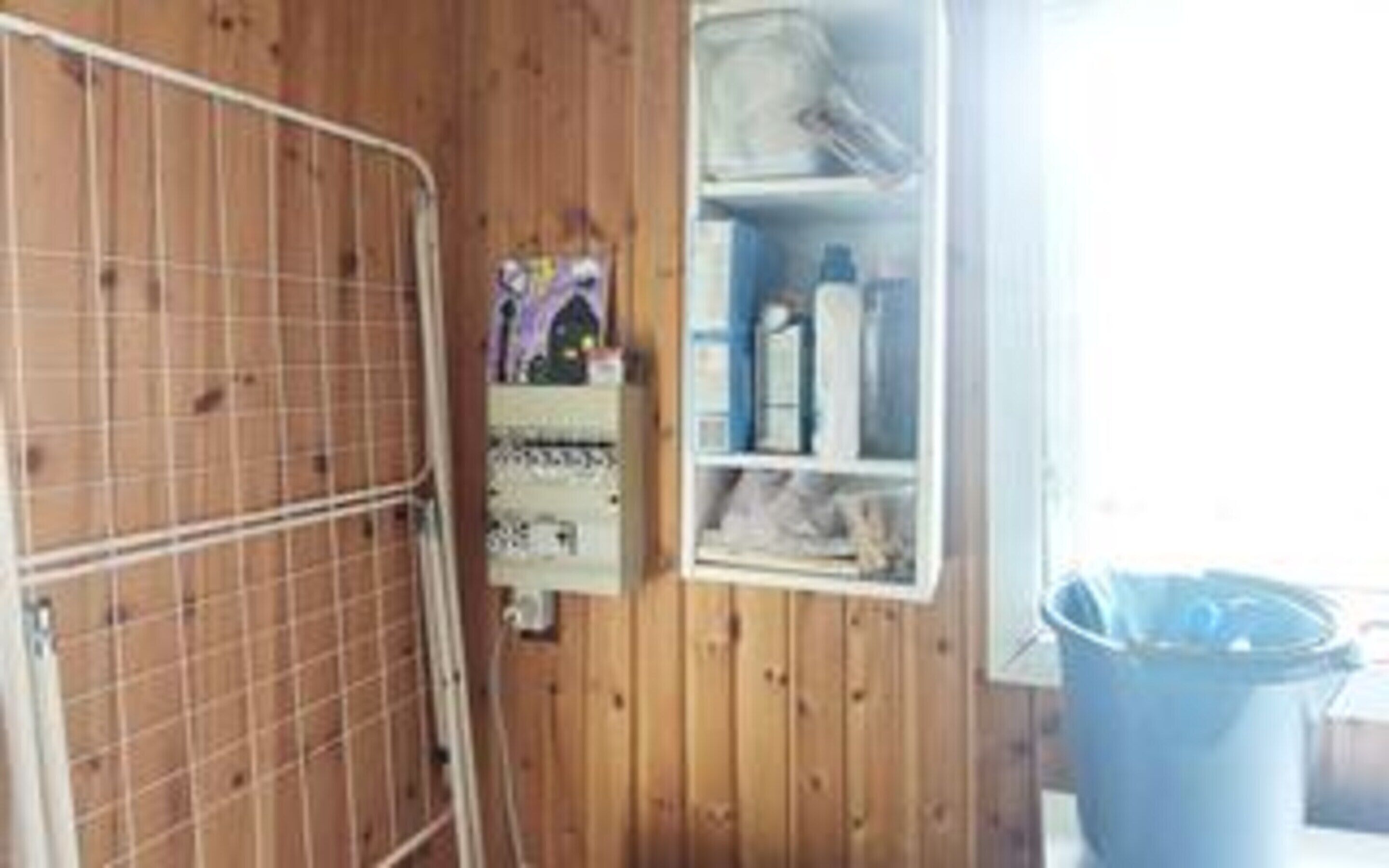 A room with a metal gate, a wooden wall, and a shelf with various items.