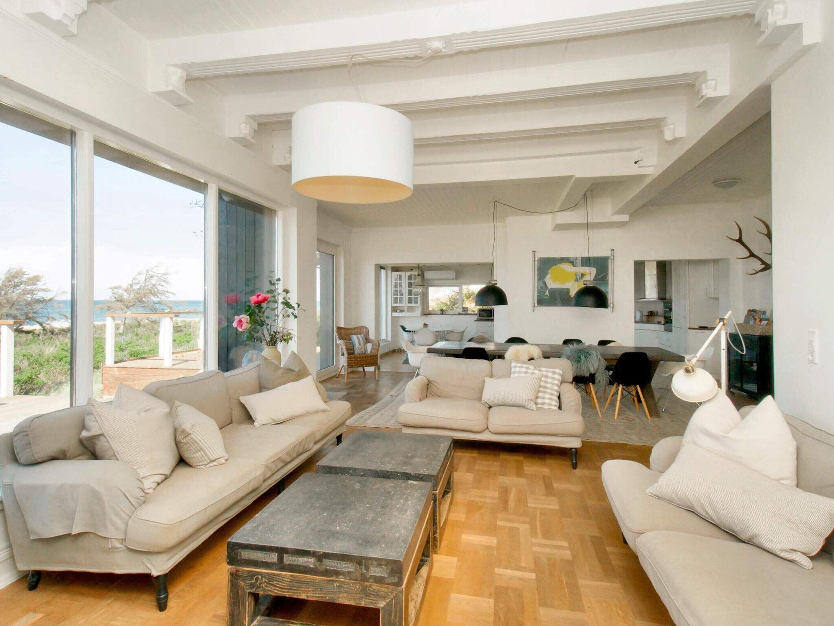 A spacious living room with a large window, a dining area, and a kitchen.