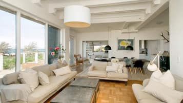Un salón amplio con un gran ventanal, un comedor y una cocina.