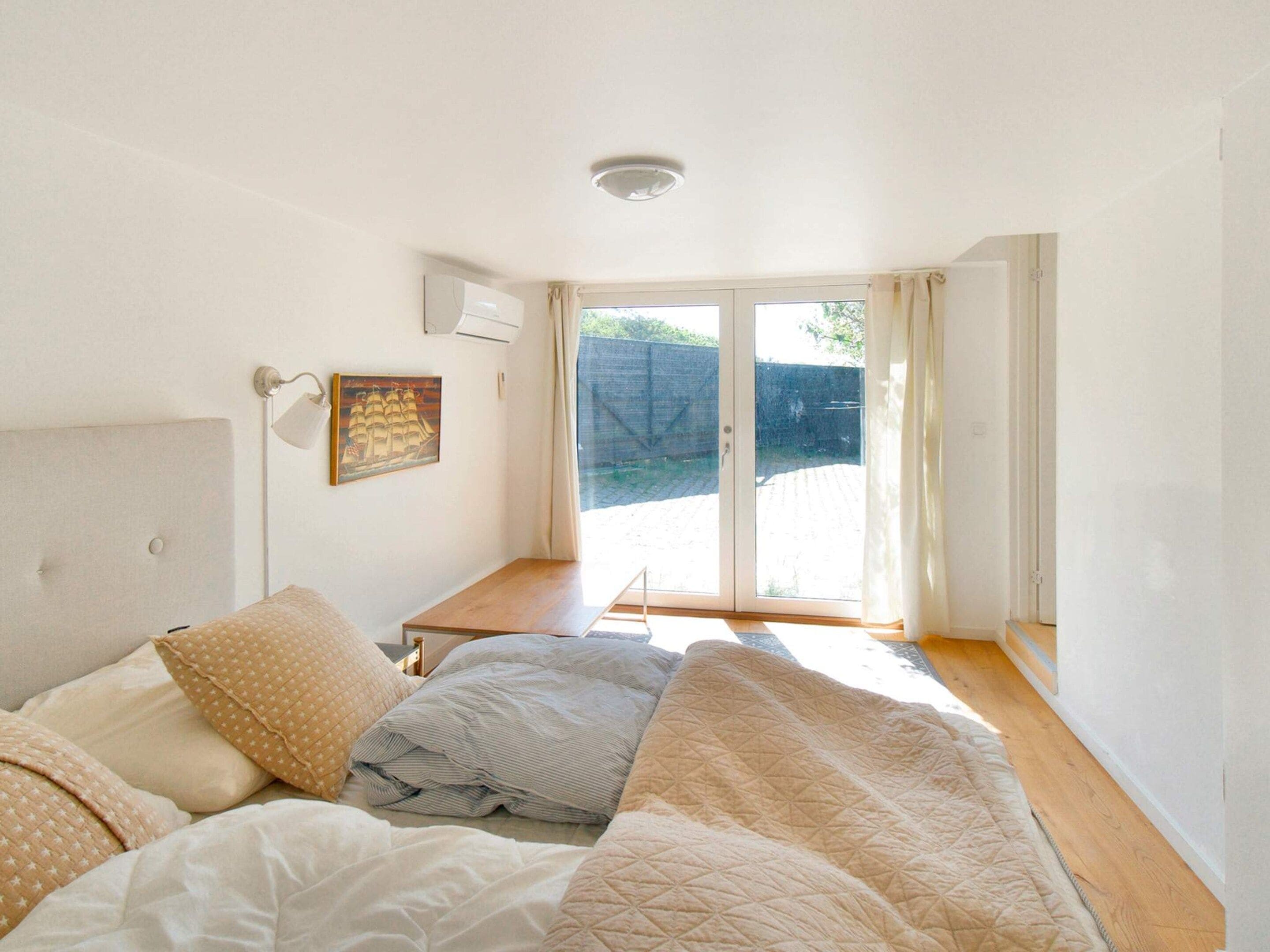 Une chambre à coucher avec un lit, un bureau et une fenêtre avec des rideaux.