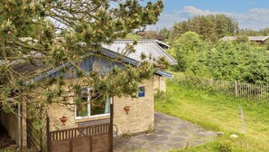 Une petite maison en pierre avec un toit en pente, un portail en bois et un chemin pavé menant à l’entrée.