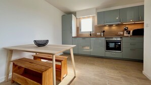 A modern kitchen with light wood cabinets, a built-in oven, and a window above the sink. - 47 Reflets- 4p-wifi-parking-vue mer (Quiberon)