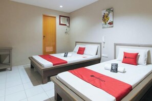 A hotel room with two single beds, a wooden nightstand, a door, a wall-mounted air conditioning unit, and a painting. - RedDoorz @ Bridgeway Hotel Tuguegarao City (Tuguegarao)