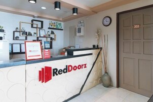 Una recepción con el logotipo de RedDoorz, un reloj y una puerta marcada con el número 203.