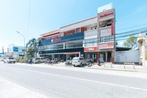 Un edificio de varios pisos con escaparate visible de motocicletas Yamaha, un hotel llamado 'Ria Hotel Bridgeway' y un cartel con el nombre 'Ria' en la planta baja.