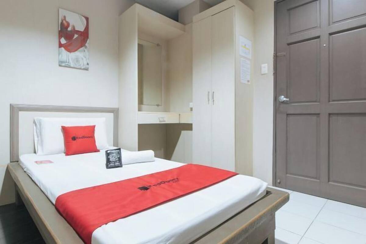 Ein Hotelzimmer mit Bett, Schrank, Spiegel und Tür.