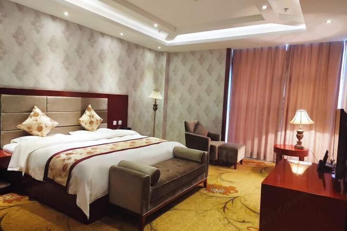 Ein Hotelzimmer mit einem großen Bett, einer Couch, einem Schreibtisch und einem Stuhl.