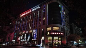 Un hotel a più piani con insegne illuminate e ampie finestre.