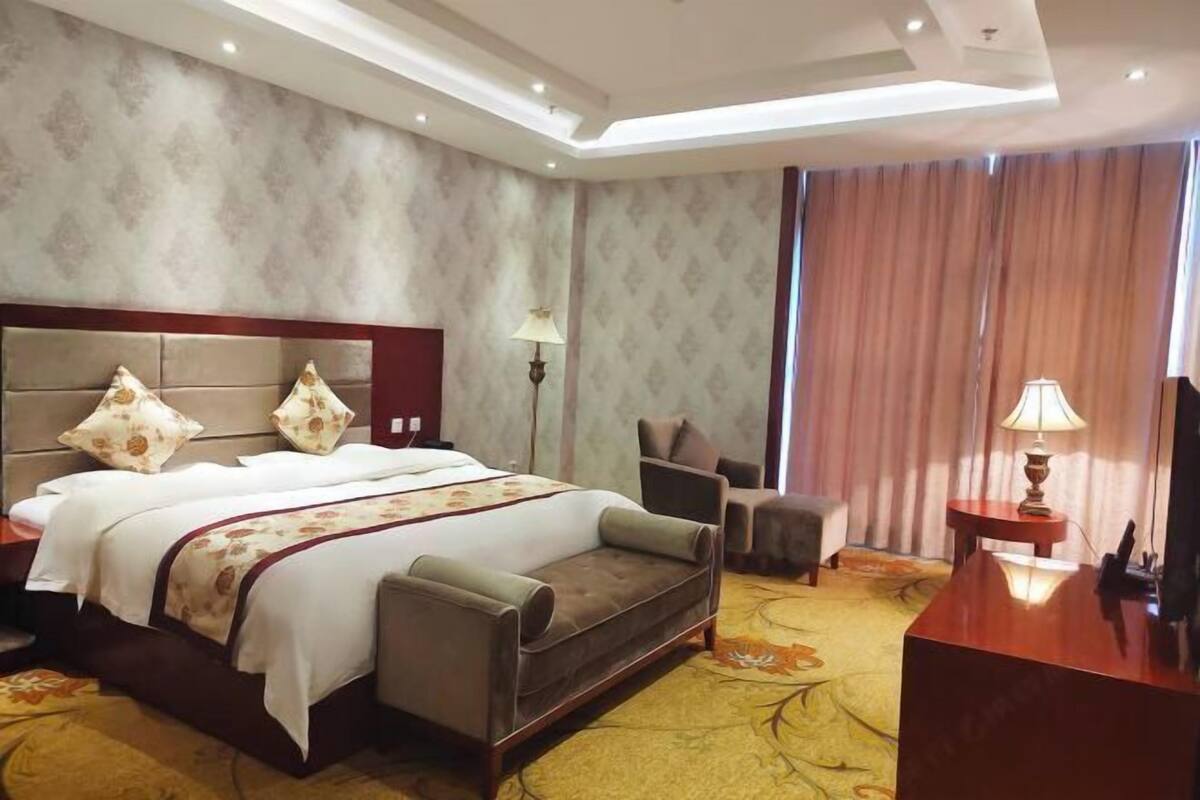 Ein Hotelzimmer mit einem großen Bett, einer Couch, einem Schreibtisch und einer Lampe.