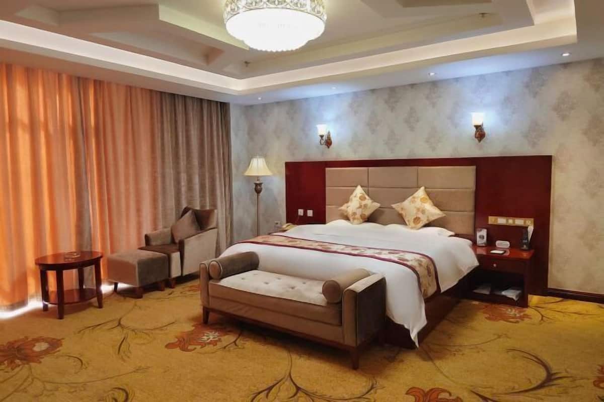 Ein Hotelzimmer mit einem großen Bett, einem Schlafsofa, einem kleinen Tisch, einem Nachttisch und einer Kandelaber.
