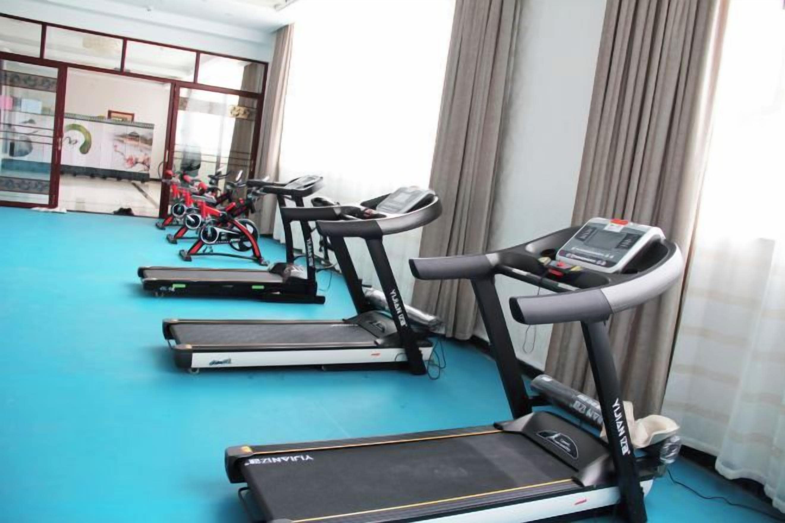 Une salle de sport équipée de tapis de course et de vélos d’exercice.