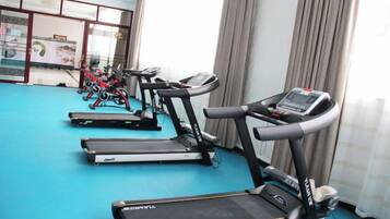 Une salle de sport équipée de tapis de course et de vélos d’exercice.