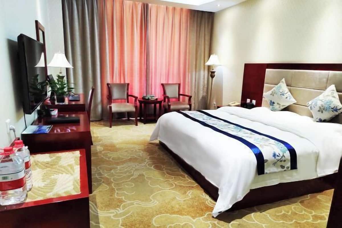Ein Hotelzimmer mit Bett, Schreibtisch, Stuhl, Fernseher und Lampe.