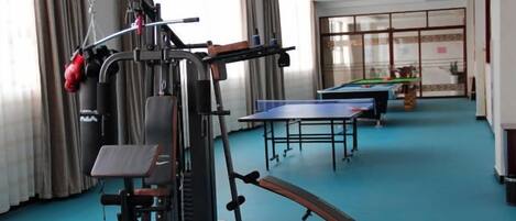 A room with exercise equipment, a ping pong table, and a billiards table.