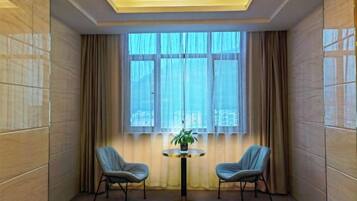 A room with a large window, two chairs, a small table with a plant, and a ceiling light fixture.