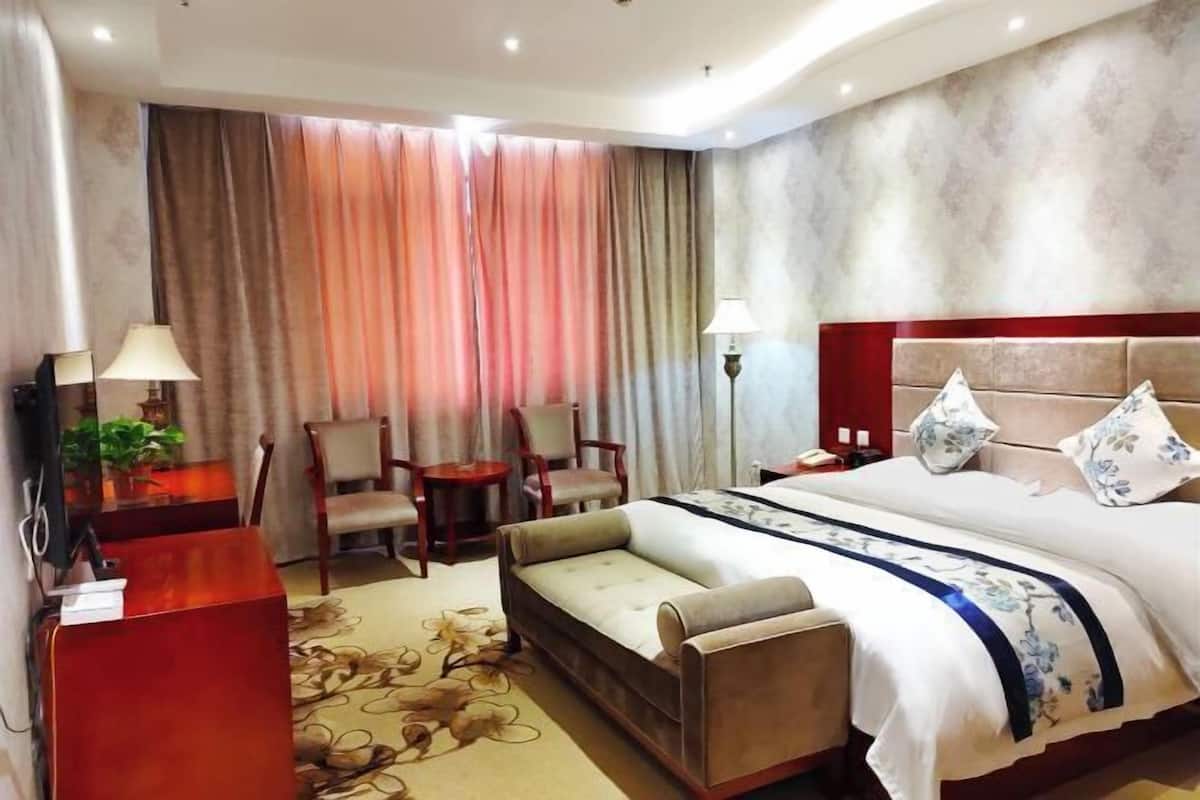 Ein Hotelzimmer mit Bett, Sofa, Schreibtisch und Stuhl.