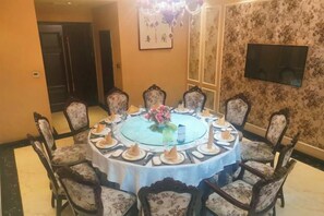 Un tavolo rotondo da pranzo con otto sedie, un lampadario e un centrotavola floreale.