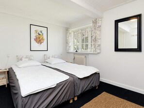 Habitación doble con cama, ventana, radiador y un cuadro en la pared.