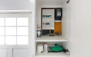 A bathroom with a toilet, sink, and storage shelves.