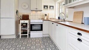 A kitchen with white cabinets, a Bosch refrigerator, a stove, and a sink. - 6 Person Holiday Home in Store Heddinge (Store Heddinge)