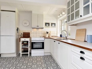 A kitchen with white cabinets, a Bosch refrigerator, a stove, and a sink. - 6 Person Holiday Home in Store Heddinge (Store Heddinge)