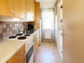 A compact kitchen with a stove, sink, and a small window. - 5 Person Holiday Home in Skummeslovsstrand (Skummesloevsstrand)