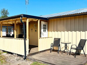 Ein Holzhaus mit einer Laube, einer Tür und zwei Stühlen.