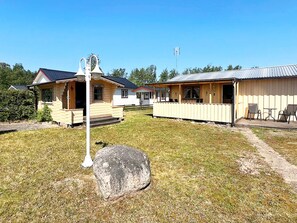 A row of cabins with a large rock in the foreground, a clear sky, and a flagpole in the background. - 5 Person Holiday Home in Skummeslovsstrand (Skummesloevsstrand)