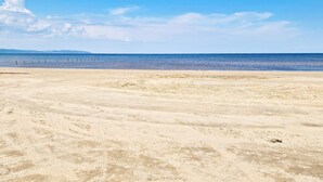 Uma praia com céu claro e mar calmo.