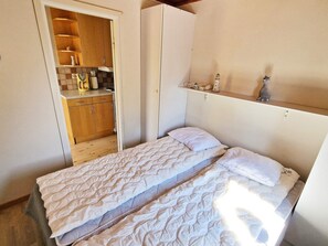 Quarto com cama, guarda-roupa e prateleira com objetos.