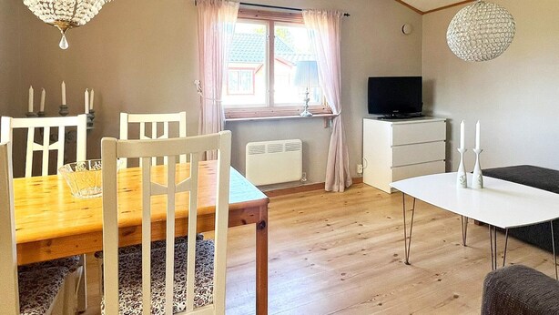 A room with a dining table, chairs, a television, and a white cabinet. - 5 Person Holiday Home in Skummeslovsstrand (Skummesloevsstrand)