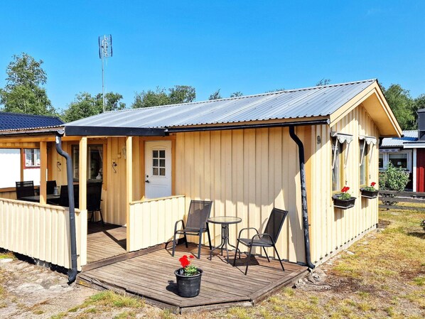 A small wooden cabin with a porch, a door, and a window.