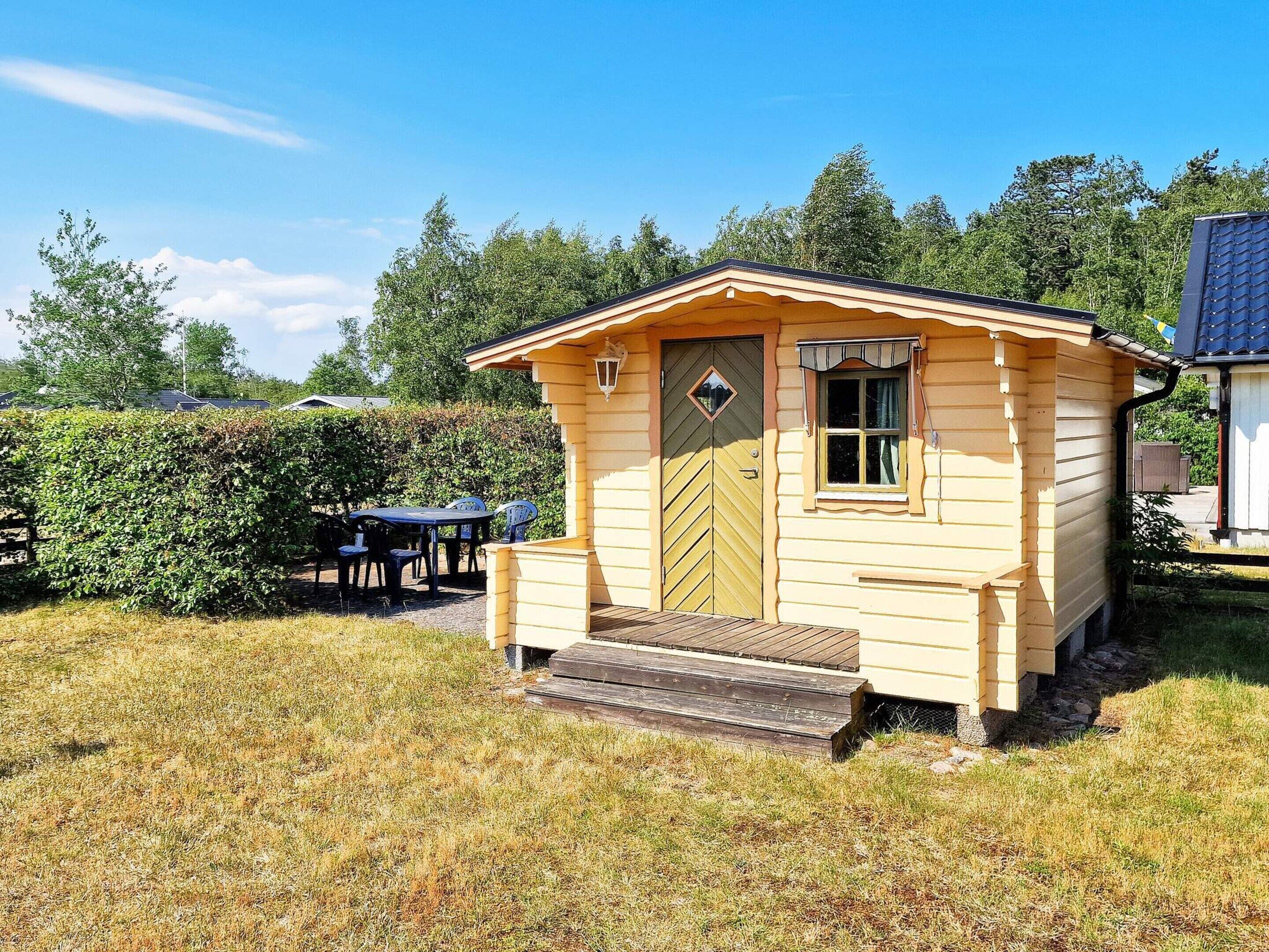 A small wooden cabin with a door, a window, and a set of stairs leading up to the entrance.