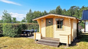 Uma pequena cabana de madeira com porta, janela e um conjunto de degraus que levam à entrada.