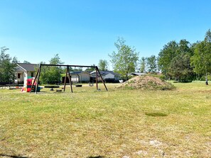 A grassy outdoor area with a swing set, a small play structure, and a pile of dirt. - 5 Person Holiday Home in Skummeslovsstrand (Skummesloevsstrand)