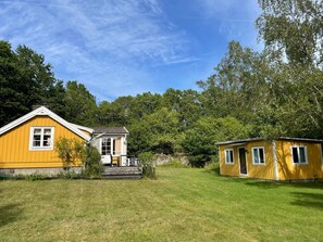 A yellow building with a small porch and a separate structure.
