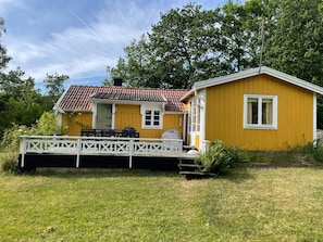 A yellow house with a red-tiled roof, a dock, and a white fence. - 6 Person Holiday Home in Ramdala (Ramdala)