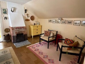 A living room with a fireplace, a yellow dresser, a patterned rug, and a sofa with decorative pillows.