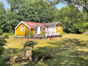 A yellow house with a red roof, surrounded by green trees and grass. - 6 Person Holiday Home in Ramdala (Ramdala)