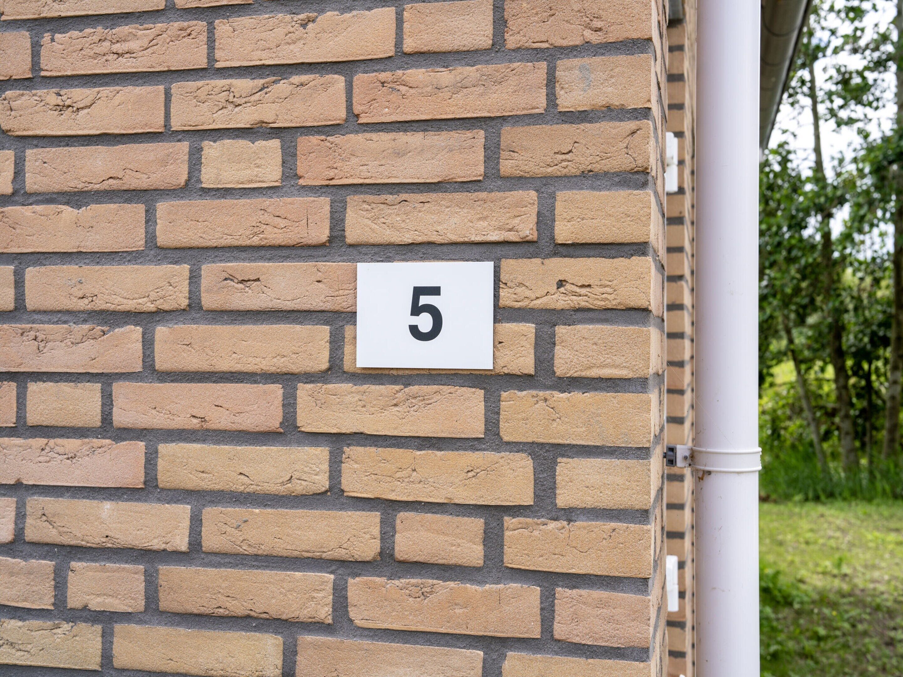 Pared de ladrillo con un letrero blanco que muestra el número 5.