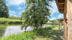 A riverside view with a wooden pavilion, a tree, and a grassy area. - Holiday Home by Lake Beach Simonshaven (Simonshaven)
