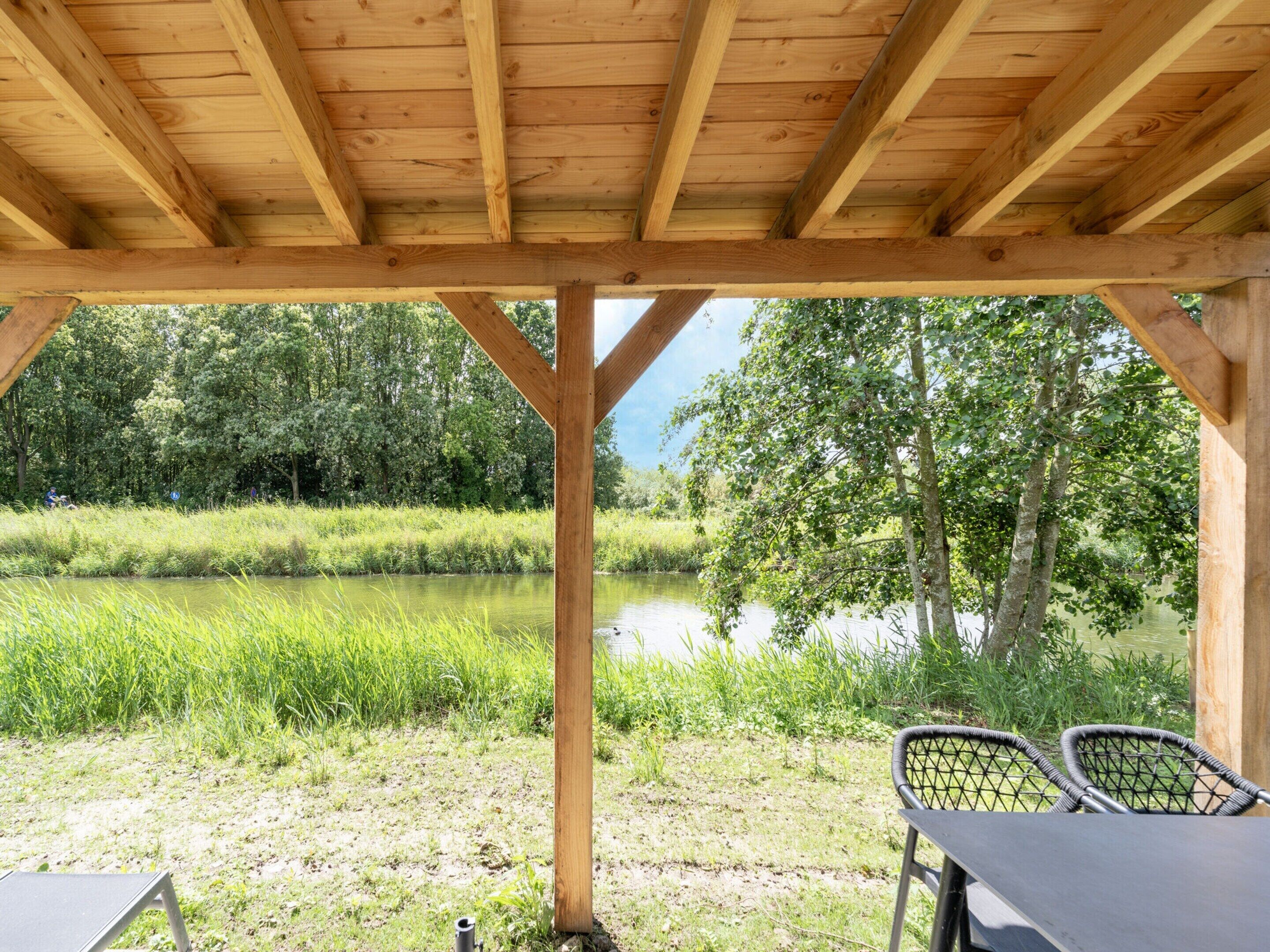 Un pavillon en bois offrant une vue sur une rivière et la verdure environnante.