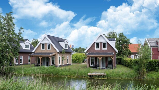 A row of houses with a pond in the foreground. - Holiday Home by Lake Beach Simonshaven (Simonshaven)