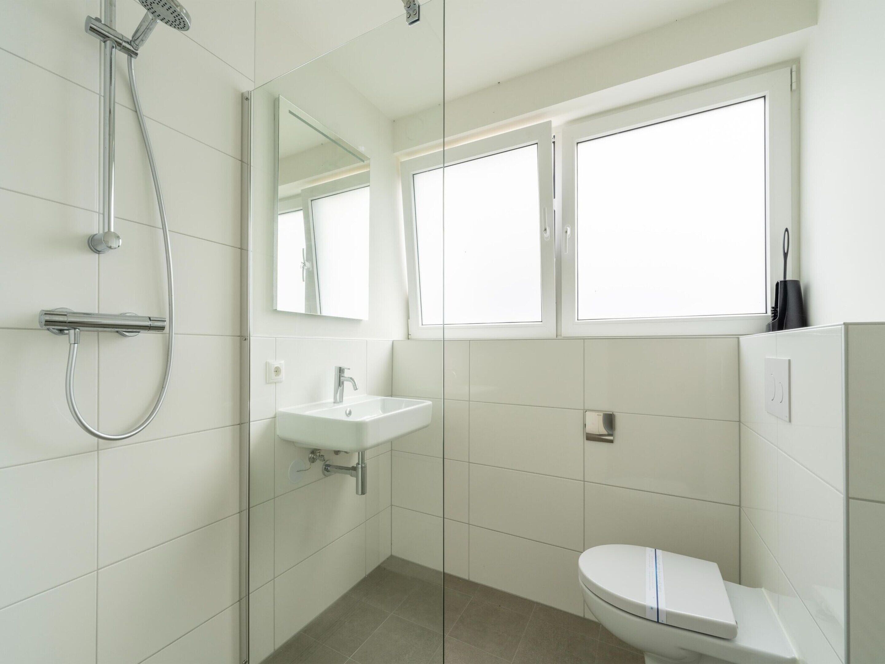 A modern bathroom with a shower, sink, and toilet.