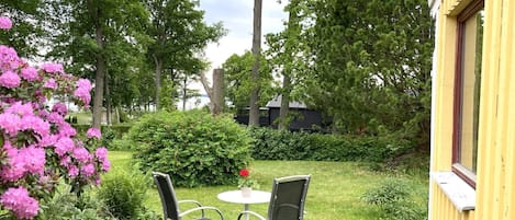 Un jardin avec deux chaises et une table, entouré d’une végétation luxuriante et de plantes en fleurs.
