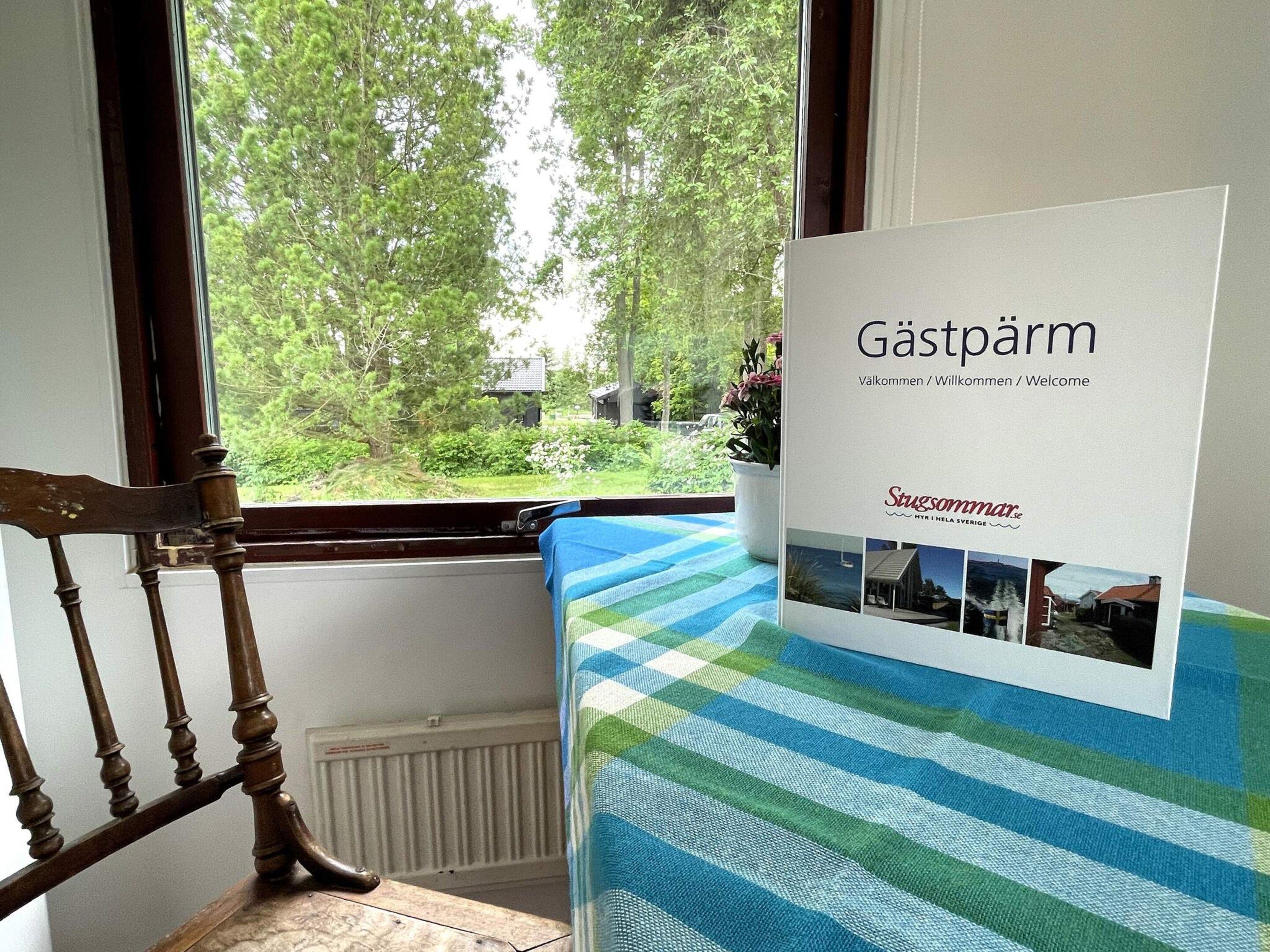 A room with a window overlooking a garden, a wooden chair, and a welcome sign.